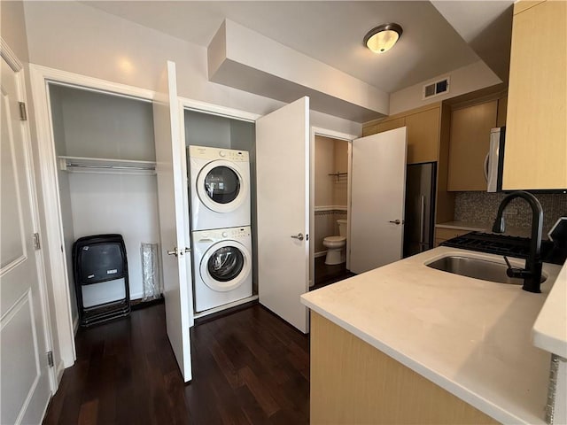 washroom with stacked washer / dryer, sink, and dark hardwood / wood-style flooring