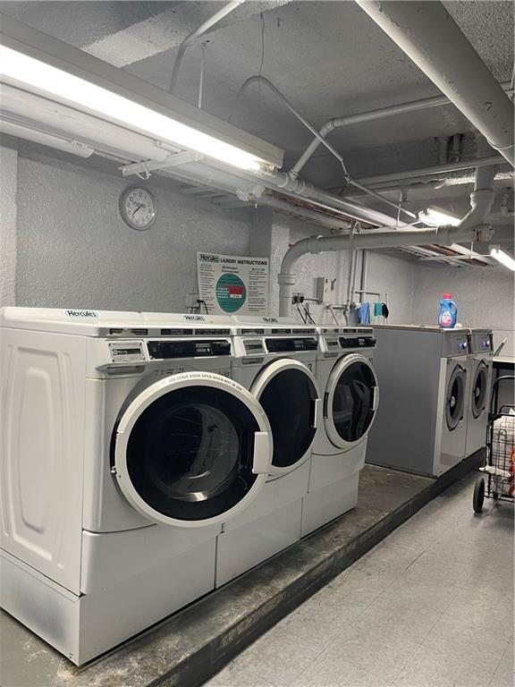 shared laundry area featuring a textured wall, washer and dryer, and light floors