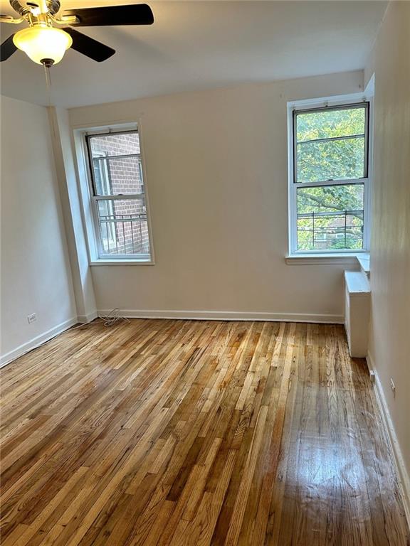 spare room with baseboards, a ceiling fan, and wood-type flooring