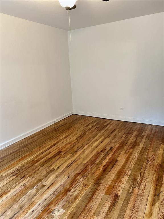 spare room featuring a ceiling fan, hardwood / wood-style flooring, and baseboards