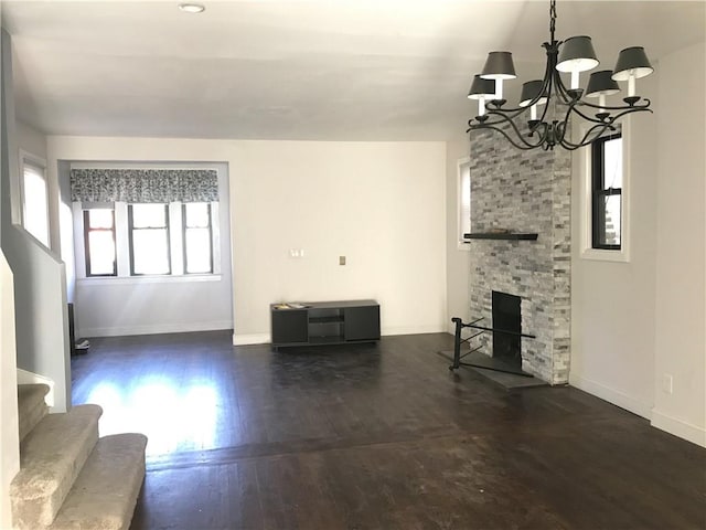 unfurnished living room featuring dark hardwood / wood-style floors, a fireplace, and an inviting chandelier