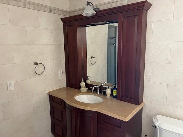 bathroom featuring toilet, tile walls, and vanity