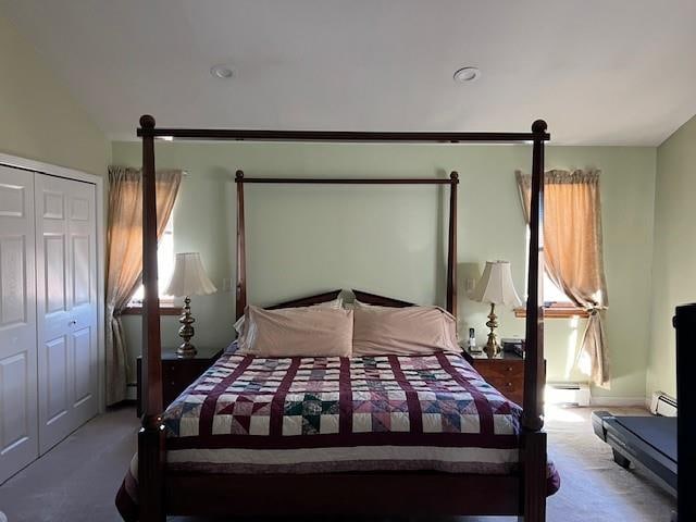 bedroom featuring a baseboard heating unit, multiple windows, and carpet