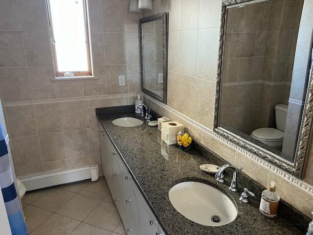 full bathroom featuring a sink, tile walls, toilet, and a baseboard radiator