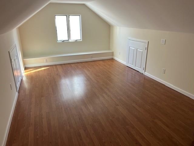 additional living space featuring baseboards, lofted ceiling, and wood finished floors