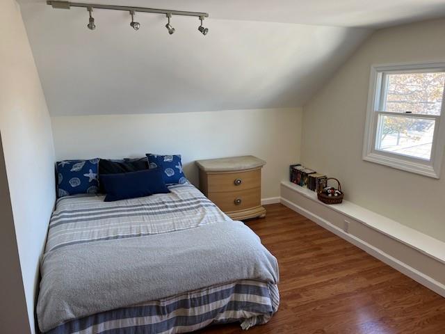 bedroom with baseboards, wood finished floors, and vaulted ceiling