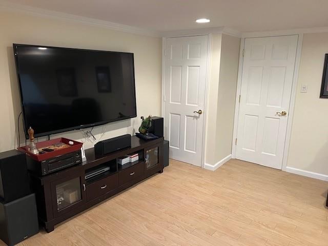 living room with baseboards, light wood-style floors, and crown molding