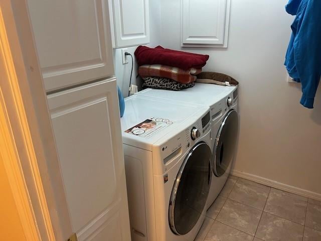 laundry area featuring washer and dryer, light tile patterned flooring, cabinet space, and baseboards