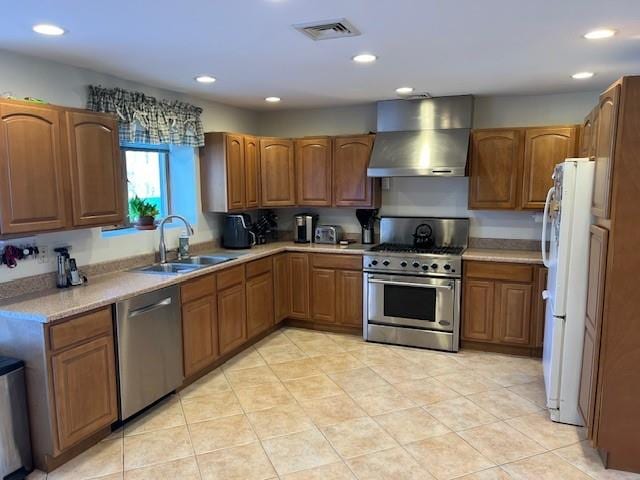 kitchen featuring visible vents, brown cabinetry, stainless steel appliances, wall chimney exhaust hood, and a sink