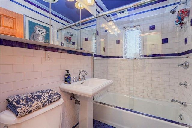 full bathroom with shower / bath combination with glass door, toilet, tile walls, and sink