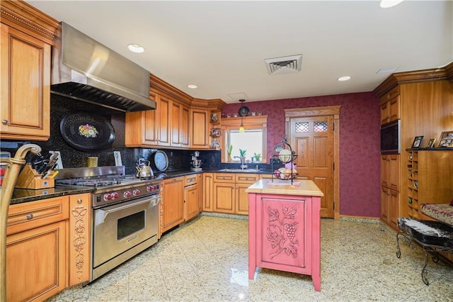 kitchen with luxury stove, wall chimney range hood, sink, tasteful backsplash, and a kitchen island