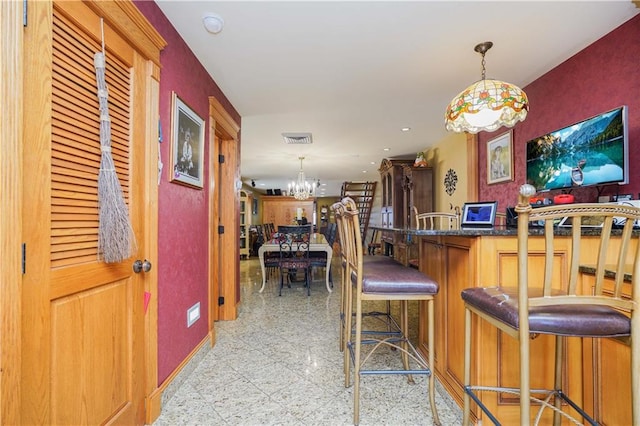 kitchen featuring a notable chandelier, a kitchen bar, kitchen peninsula, and hanging light fixtures