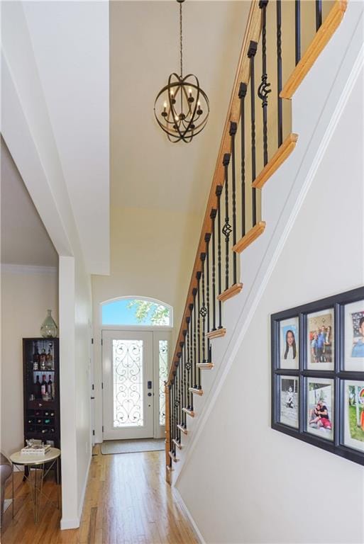 foyer entrance with crown molding, hardwood / wood-style floors, a chandelier, and a high ceiling