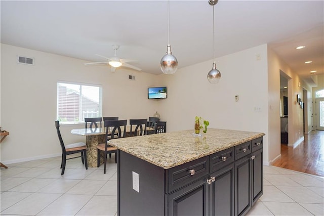 kitchen featuring pendant lighting, a center island, light tile patterned floors, and ceiling fan