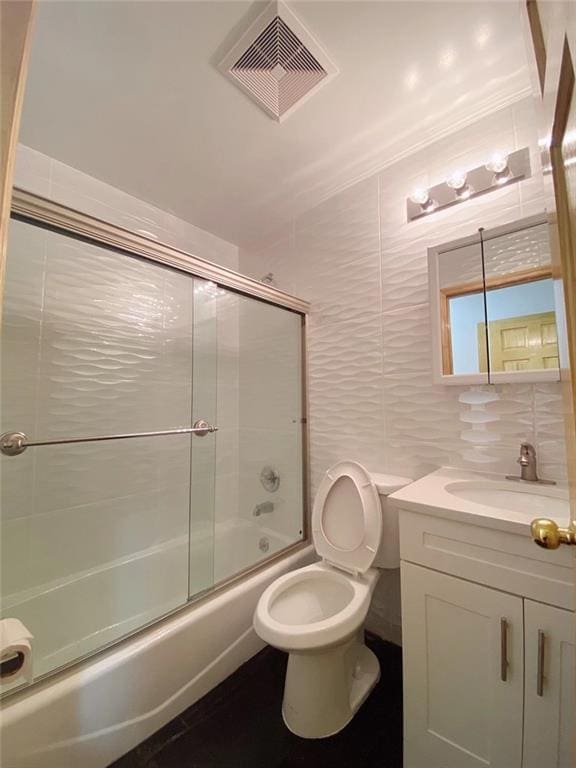 full bathroom featuring decorative backsplash, combined bath / shower with glass door, vanity, tile walls, and toilet