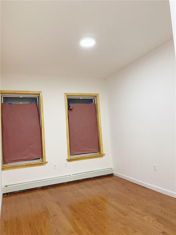 empty room with hardwood / wood-style floors and baseboard heating