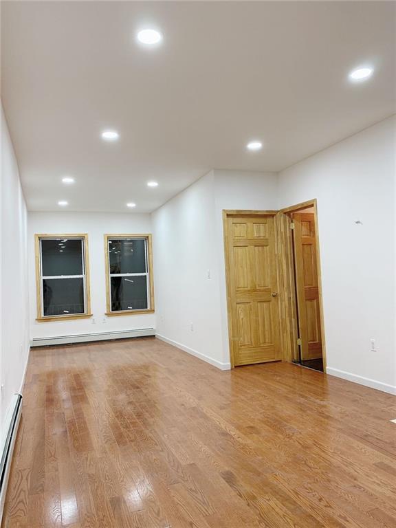 spare room featuring wood-type flooring and a baseboard radiator