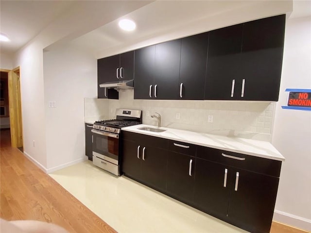 kitchen featuring tasteful backsplash, sink, light hardwood / wood-style flooring, and stainless steel gas range