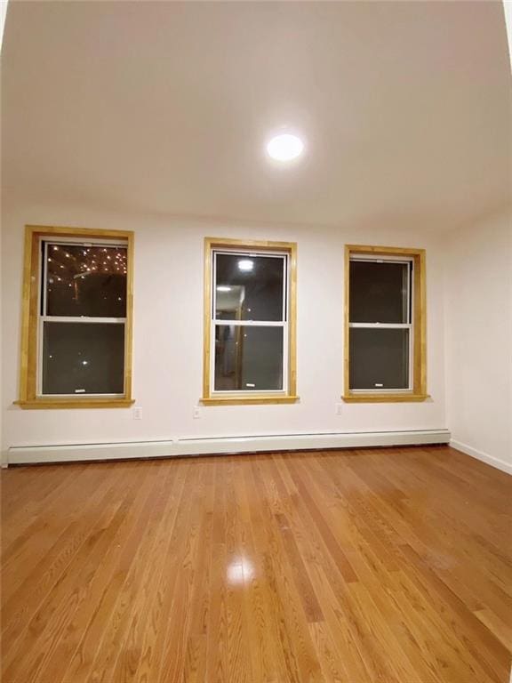 unfurnished room featuring a baseboard radiator and light hardwood / wood-style flooring