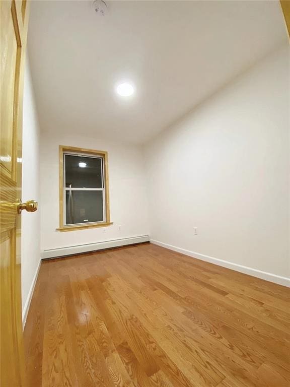 unfurnished room featuring a baseboard radiator and light wood-type flooring