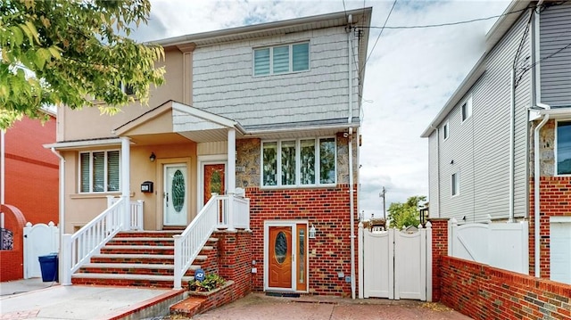 view of front of property with brick siding, fence, a gate, and stucco siding