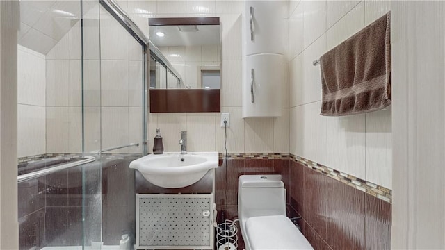 bathroom featuring toilet, a stall shower, tile walls, and vanity