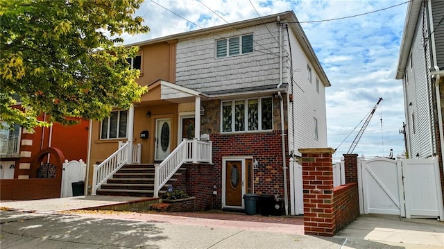 view of front of house featuring a gate, brick siding, and fence