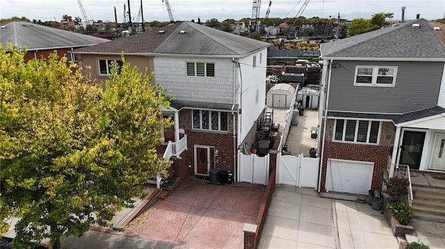 view of front of house with driveway, an attached garage, a gate, fence, and brick siding