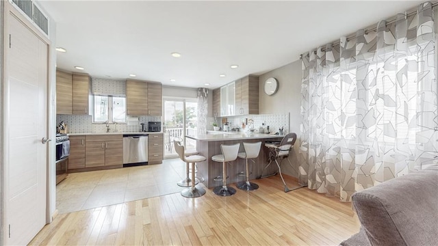 kitchen with dishwasher, light countertops, visible vents, and brown cabinets