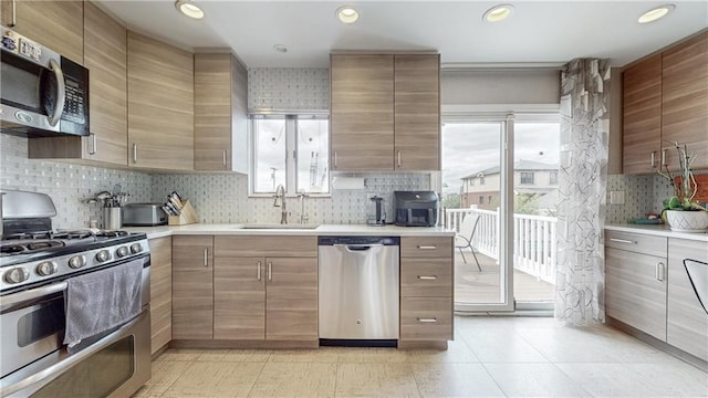 kitchen featuring recessed lighting, light countertops, backsplash, appliances with stainless steel finishes, and a sink