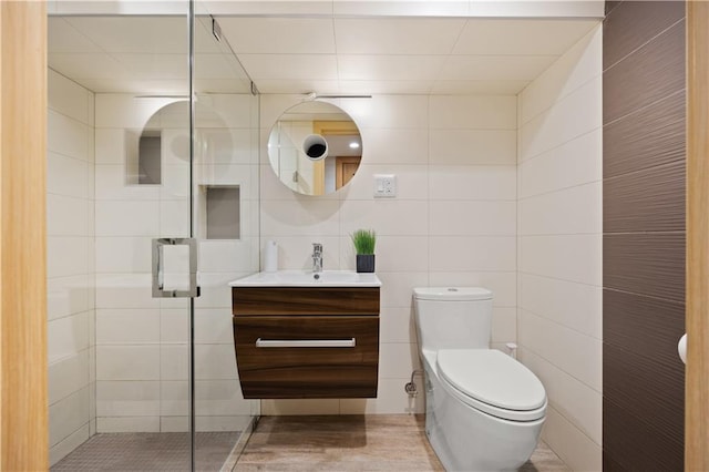 bathroom featuring tile walls, walk in shower, vanity, and toilet