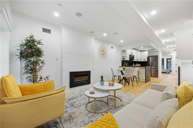 living room featuring crown molding, a fireplace, and light hardwood / wood-style floors