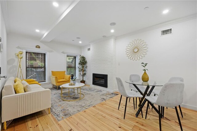 living room featuring hardwood / wood-style floors, ornamental molding, and a large fireplace