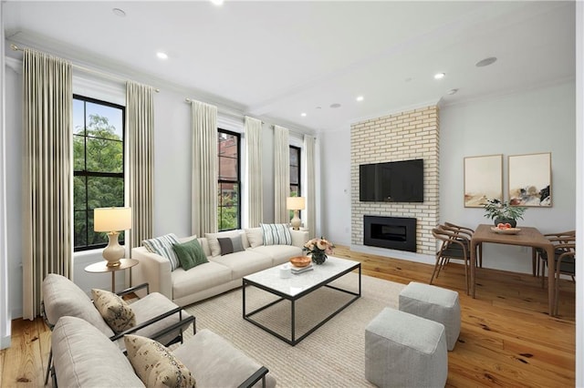 living room with a healthy amount of sunlight, a brick fireplace, and light hardwood / wood-style flooring