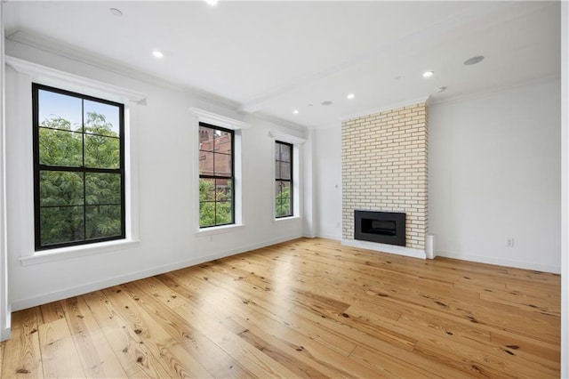 unfurnished living room featuring a brick fireplace, ornamental molding, and light hardwood / wood-style floors