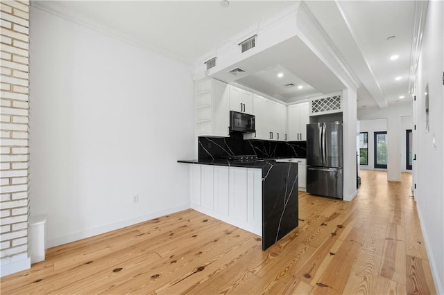 kitchen with dark countertops, visible vents, black microwave, a peninsula, and freestanding refrigerator