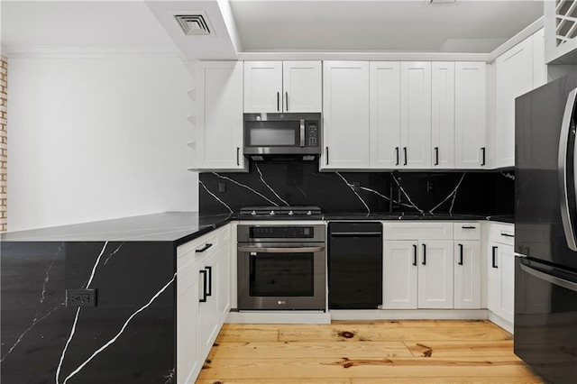 kitchen with stainless steel microwave, visible vents, oven, freestanding refrigerator, and stove