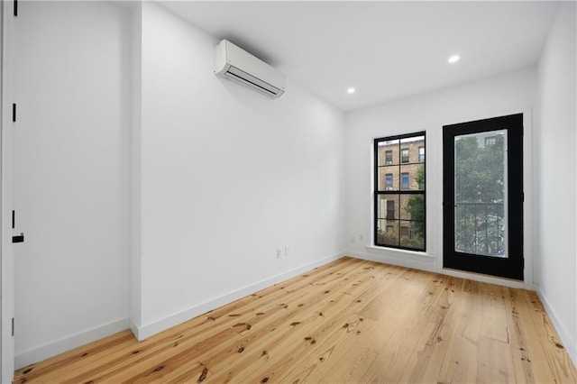 unfurnished room with a wall mounted AC and hardwood / wood-style flooring