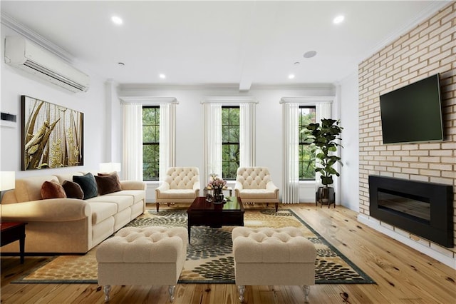 living room with a wall mounted air conditioner, a fireplace, light wood-type flooring, crown molding, and beam ceiling