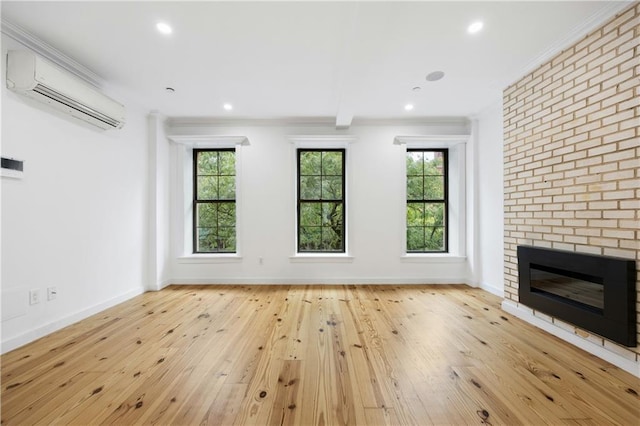 unfurnished living room featuring a brick fireplace, light wood-type flooring, ornamental molding, a wall mounted air conditioner, and beamed ceiling