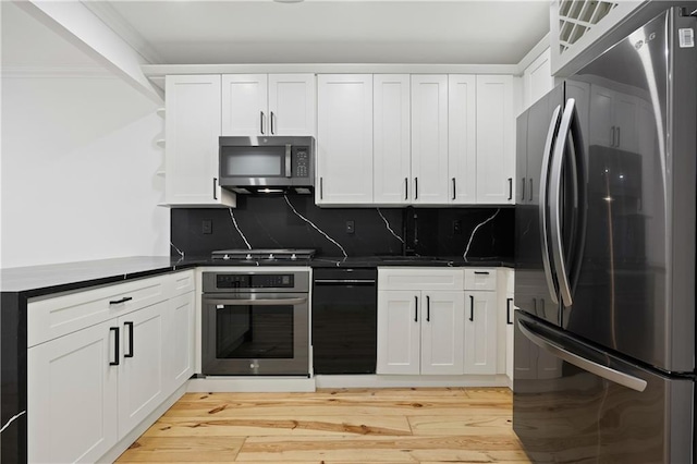 kitchen featuring stainless steel appliances, white cabinetry, and backsplash