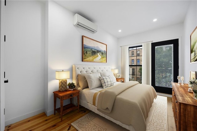 bedroom with a wall unit AC and light hardwood / wood-style flooring