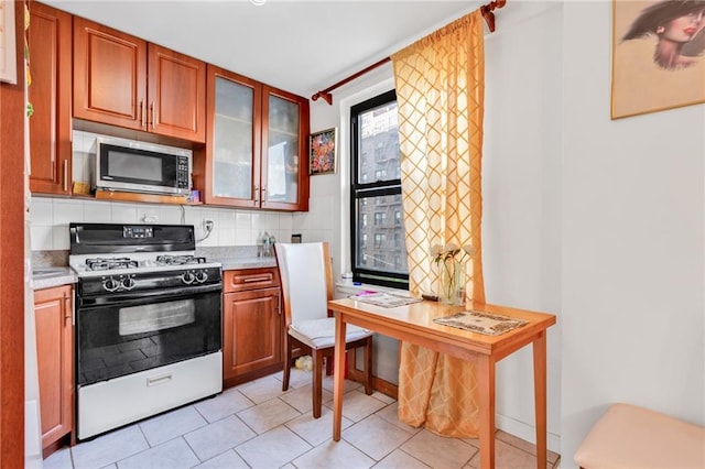 kitchen featuring decorative backsplash, white gas range, and light tile patterned flooring