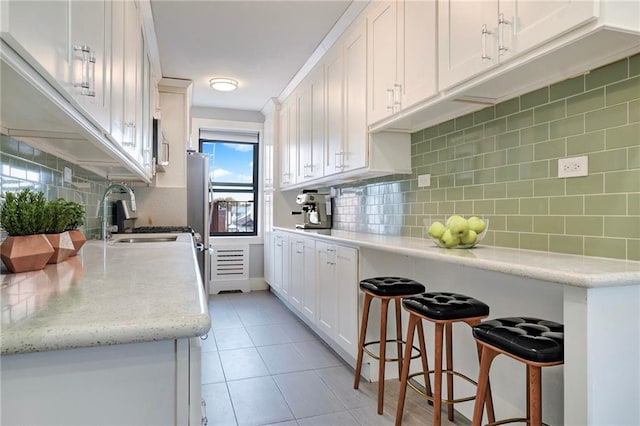 kitchen with a kitchen bar, white cabinets, and backsplash