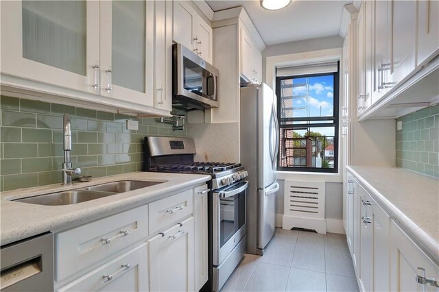 kitchen with backsplash, sink, light tile patterned flooring, appliances with stainless steel finishes, and white cabinets