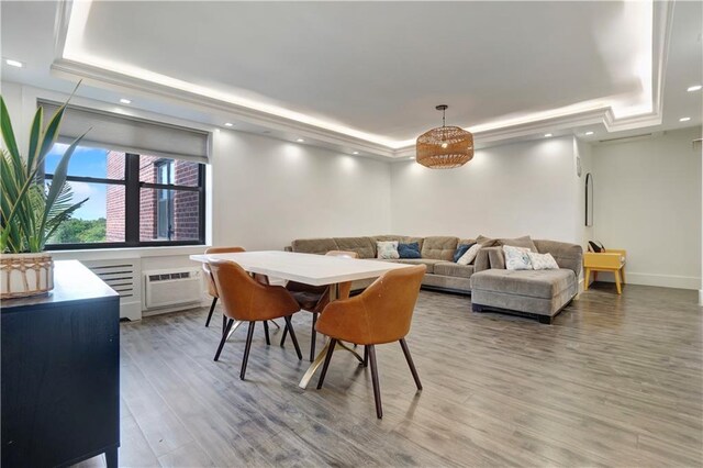 dining area with a raised ceiling, wood-type flooring, and a wall mounted air conditioner