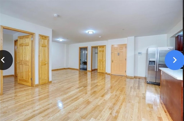 interior space with light hardwood / wood-style floors and stainless steel fridge with ice dispenser