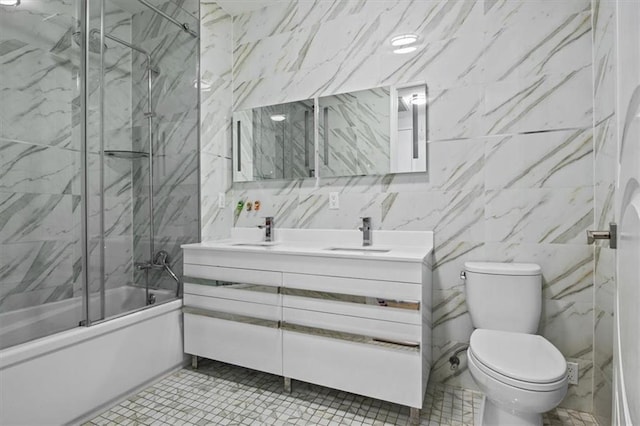 full bathroom with vanity, shower / bath combination with glass door, tile patterned flooring, toilet, and tile walls