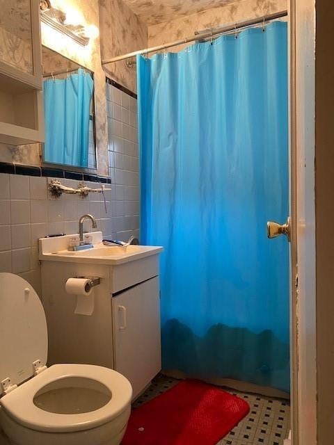 bathroom with sink, toilet, and tile walls