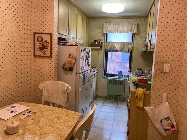 kitchen featuring cream cabinets, radiator heating unit, and white fridge